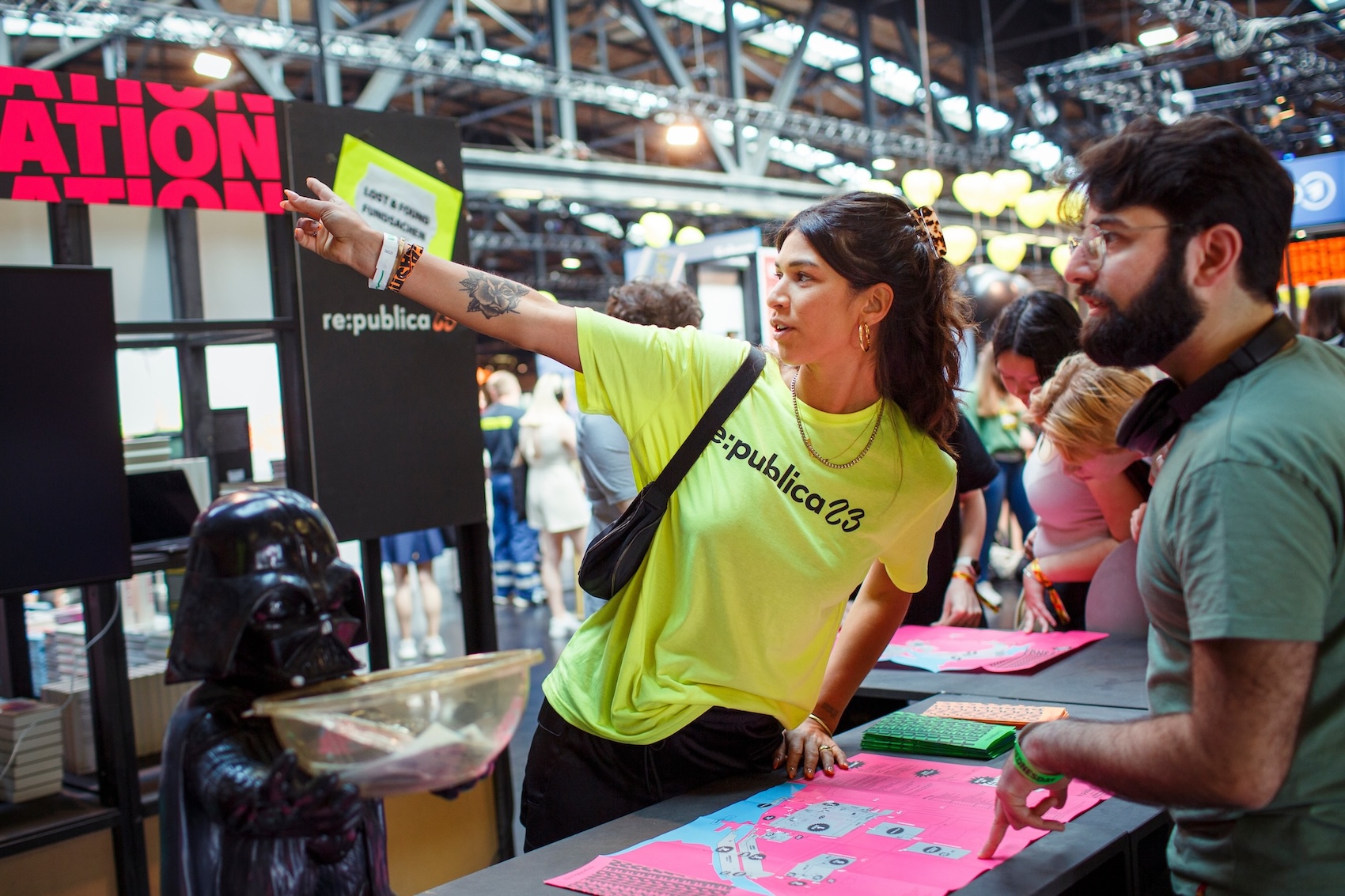 Eine Helfer*in zeigt einem Teilnehmer den Weg.